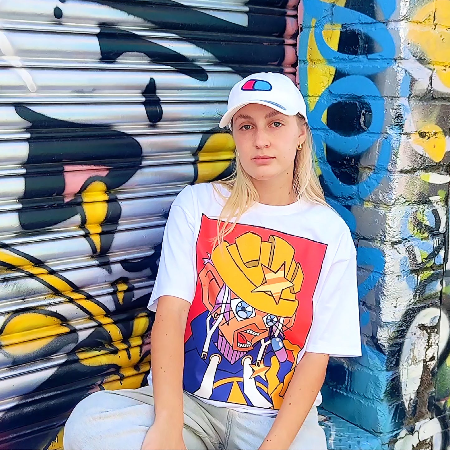 Girl Model Jordyn is sitting down, posing and  wearing (anime inspired graphic t) Mahou Shounen Star-B T Shirt 